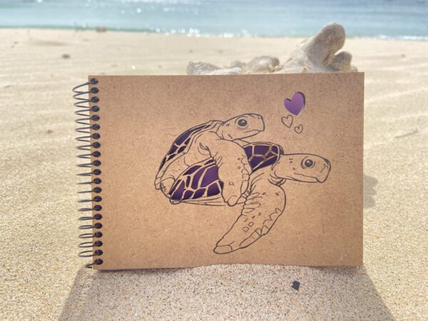 caderno lilás com tartarugas e corações na areia